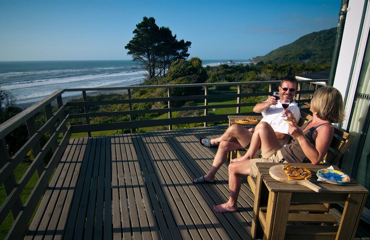 Guests enjoying homemade pizza on the deck with views to Tasman Sea